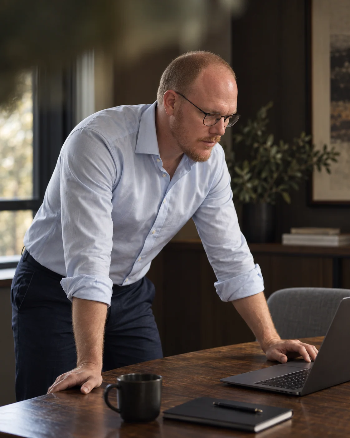 Daniel Brownlie working at his desk in warm window light